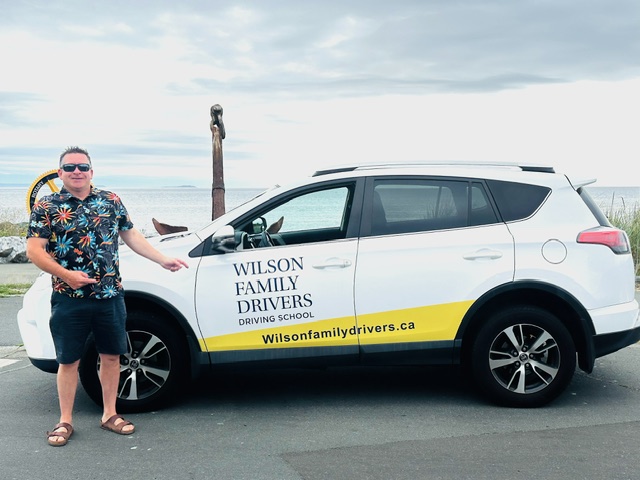 Kallin Wilson in front of Wilsons Family Drivers' school car